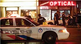  ?? — AFP ?? Toronto police officers walk the scene at Danforth St. at the scene of a shooting in Toronto, Ontario on Monday.