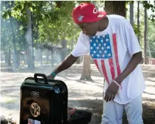  ?? Staff photos by Forrest Talley ?? above Retired Marine Dailean Johnson celebrates the Fourth of July by cooking out Tuesday at Elliot Lake in Bowie County.