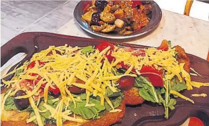  ??  ?? UN CLÁSICO. La milanesa es una de las especialid­ades de la casa. En este caso, viene con queso, rúcula, jamón y tomates.