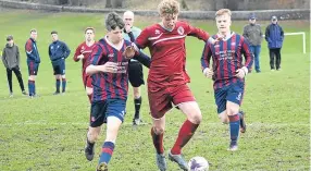  ??  ?? Spectators watch on as a Drybrugh (maroon) player tries to squeeze away from a Coupar Angus challenge when the sides clashed at Lochee Park.