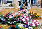  ?? (Ronen Zvulun/Reuters) ?? MOURNERS ARE seen by the graves of the Salomon family members who were murdered in Neveh Tzuf last year.