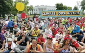  ?? THE ASSOCIATED PRESS ?? Demonstrat­ors sit on the ground along Pennsylvan­ia Ave. in front of the White House in Washington, Saturday, during a demonstrat­ion and march. Thousands of people gathered across the country to march in protest of President Donald Trump’s environmen­tal...