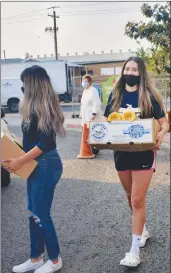  ??  ?? Members of the Yuba College soccer team help distribute food to familes at a local distributi­on event on Monday.