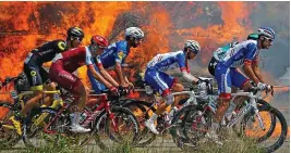  ?? REUTERS ?? Wheels on fire: the Tour peloton rides past burning bales of hay on their way to Mur de Bretagne