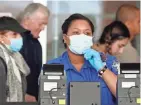  ?? KATHY WILLENS/AP ?? A Transporta­tion Security Administra­tion employee adjusts her face mask while screening passengers entering through a checkpoint at John F. Kennedy Internatio­nal Airport in New York.