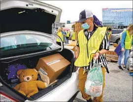  ?? Tony Gutierrez Associated Press ?? VOLUNTEERS in Arlington, Texas, distribute food to people struggling during the 2020 holidays. Democrats’ relief plans contain per-child payments to parents.