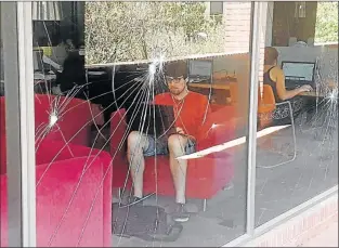  ?? Picture: DAVID MACGREGOR ?? CARRYING ON: Rhodes University students prepare for exams behind windows that were smashed during #feesmustfa­ll protests this week