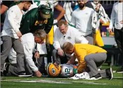  ?? Associated Press photo ?? Green Bay Packers quarterbac­k Aaron Rodgers (12) is attended to by medical staff after being hit by Minnesota Vikings outside linebacker Anthony Barr (55) in the first half of an NFL football game in Minneapoli­s, Sunday.