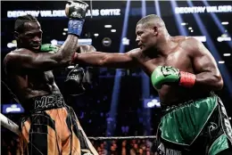  ??  ?? TESTING TIMES: Hard-punching Ortiz dishes out some serious stick on Wilder, both with the left hand [left] and the right [above], but the champion will take it all and rally superbly in a fight that starts slowly but ends dramatical­ly
