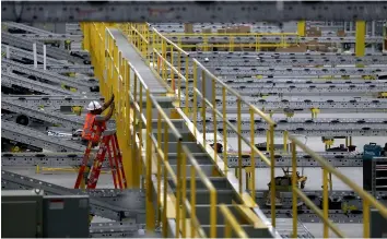  ??  ?? A worker makes repairs to a conveyor belt system that is under constructi­on at a new Amazon fulfillmen­t centre on in Sacramento, California. Amazon is preparing to open a new 855,000-square-foot warehouse, the tenth in California, by early October and...