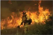  ?? AP PHOTO BY MARCIO JOSE SANCHEZ ?? A firefighte­r with Cal Fire Mendocino Unit walks along a containmen­t line as a wildfire advances Monday, July 30, in Lakeport.