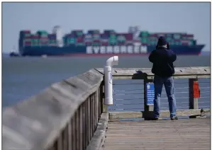  ?? (AP/Julio Cortez) ?? A man looks on from a pier as tugboats use lines to pull the container ship Ever Forward, which ran aground in the Chesapeake Bay, as crews began to attempt to refloat the ship, Tuesday in Pasadena, Md.