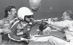  ?? Ric Feld/Associated Press ?? Bobby Allison, center, holds Cale Yarborough’s foot after Yarborough, right, kicked him following the 1979 Daytona 500.