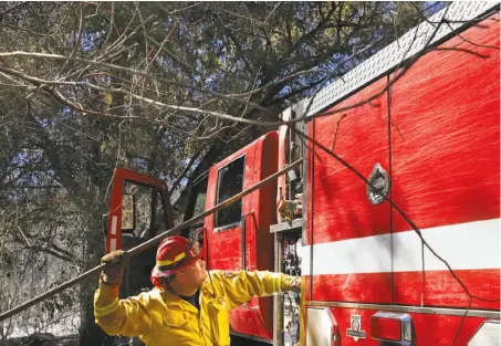  ?? Photos by Leah Millis / The Chronicle ?? Fire Captain Kevin Bowman feeds a water hose to his crew as they battle the Tassajara Fire in Monterey County on Tuesday.