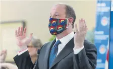  ?? David Zalubowski, The Associated Press ?? Gov. Jared Polis dons a mask Friday in Centennial to encourage state residents to wear them while in public to reduce the spread of the new coronaviru­s.
