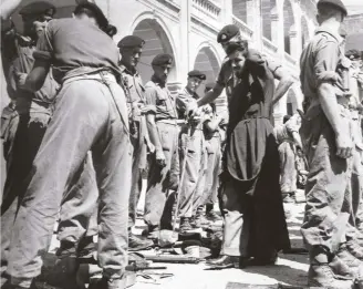  ??  ?? ABOVE: Soldiers of the Suffolk Regiment are searched by their own officers outside Kykko Monastery in the presence of a monk, September 1958