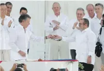  ?? FERNANDO VERGARA, THE ASSOCIATED PRESS ?? Colombian President Juan Manuel Santos, left, gives a pin to the top commander of the Revolution­ary Armed Forces of Colombia, FARC, Rodrigo Londono, after they signed a peace agreement in Cartagena, Colombia, Monday.