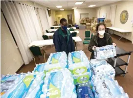  ?? STAFF PHOTO BY TROY STOLT ?? Samuel Brand and Vanisha Bonilla stack cases of donated water bottles inside of Orchard Park SDA church during a water bottle drive to help residents of Jackson, Miss., who have been without water for nearly a month, after freezing temperatur­es burst water mains in February.