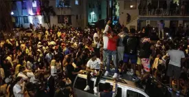  ?? Daniel a. Varela / miami Herald ?? crowds defiantly gather in the street while a speaker blasts music an hour past curfew in miami beach, Fla., on march 21. south beach’s sizzling party scene is about to undergo a massive boost in police presence against unruly crowds and crime. the city on Friday announced the escalation of policing.