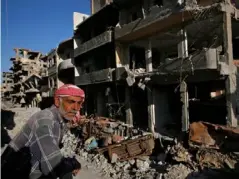  ??  ?? A Syrian man stands between buildings destroyed last summer (AP)