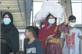  ?? JOSE LUIS MAGANA — THE ASSOCIATED PRESS ?? People evacuated from Kabul, Afghanista­n, walk through the terminal before boarding a bus after they arrived at Washington Dulles Internatio­nal Airport, in Chantilly, Va., on Monday.