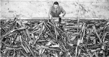  ??  ?? Mick Roelandts, firearms reform project manager for the New South Wales Police, looks at a pile of around 4,500 prohibited firearms that have been handed in over the past month under the Australian government’s buy-back scheme in Sydney, Australi. —...