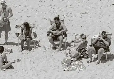  ?? Andrew Mills / NJ Advance Media via Associated Press ?? New Jersey Gov. Chris Christie, right, relaxes at Island Beach State Park on Sunday with family and friends. Christie defended his visit, saying he had announced his vacation plans before the government shutdown.