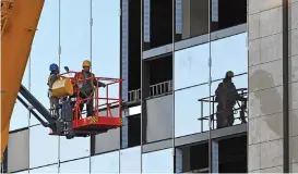  ?? (AFP) ?? Workers prepare to install a window panel at a constructi­on site in Beijing on Tuesday