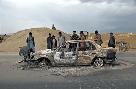  ?? RAHMAT GUL/AP ?? Afghans examine a burnt vehicle following an attack that claimed four U.S. lives in 2019 near the Bagram Air Base in Afghanista­n. The Taliban claimed responsibi­lity for the attack.