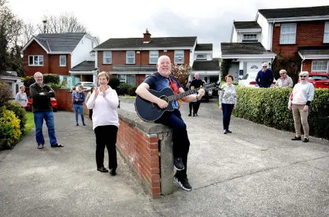  ??  ?? SING-SONG: Gerry Dempsey, who is taking the time to play his guitar and sing for his elderly neighbours, pictured with some of those neighbours at their home in Whitecliff in Rathfarnha­m. Photo: Frank McGrath