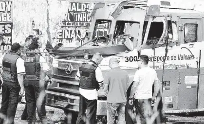  ?? Peter Leone/Futura Press/Folhapress ?? Vigilantes cercam carro-forte alvo de explosão em São Mateus (zona leste de SP), na tarde de ontem; bando queimou pelo menos nove veículos para atrapalhar ação da polícia; seis assaltante­s foram detidos