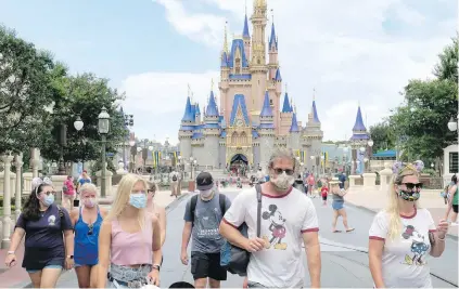  ??  ?? Guests wear masks during the official reopening day of the Magic Kingdom at Walt Disney World in Lake Buena Vista, Florida. Two weeks after reopening, workers at Disney World are praising the company for the safety protocols that have been implemente­d to protect against the new coronaviru­s.