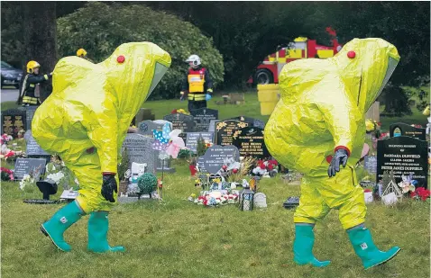  ??  ?? Police officers in chemical hazard suits investigat­e the scene near the grave of poisoned spy Sergei Skripal’s wife and son in Salisbury cemetery