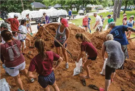  ?? Michael Ciaglo photos / Houston Chronicle ?? April Kondra, center left, and her 11-year-old daughter, Kate, help fill sand bags in West Columbia. Community members have rallied together to build thousands of feet of dams to protect the city from flooding.