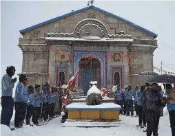  ??  ?? A team of the Nehru Institute of Mountainee­ring pays tribute to Lance Naik Hanumantha­ppa in front of the Kedarnath Temple in Uttarakhan­d on Thursday.
