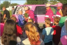  ?? Photo by Susan Holland ?? Brooklyn Carte, a Gravette fifth-grader who is battling cancer, receives a bouquet of flowers from Chris Noeldner, a member of the Pink Heals tour, at Gravette Upper Elementary School on Oct. 9. Other tour members, Jeff Rand and Seth Kallick, look on,...