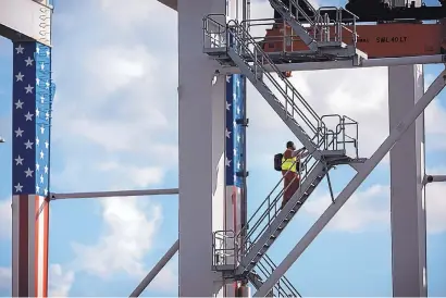  ?? AP PHOTO/STEPHEN B. MORTON ?? A rubber tire gantry operator climbs to his cab at the Port of Savannah in Georgia. The global economy is showing signs of weakening, with the United States, China and Europe all facing the rising threat of a slowdown.