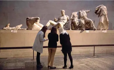  ?? (AP Photo/matt Dunham, File) ?? Women stand by a marble statue of a naked youth thought to represent Greek god Dionysos, center, from the east pediment of the Parthenon, on display during a media photo opportunit­y to promote a forthcomin­g exhibition on the human body in ancient Greek art at the British Museum in London Jan. 8, 2015. The British Museum has pledged not to dismantle its collection following a report that the institutio­n’s chairman has held secret talks with Greece’s prime minister over the return of the Parthenon Sculptures, also known as the Elgin Marbles.