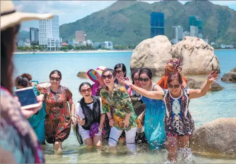  ?? LINH PHAM / GETTY IMAGES PROVIDED TO CHINA DAILY ?? Above: Chinese tourists pose for photos near rocks at the Hon Chong scenic site in Nha Trang, Vietnam. With a total of 2.7 million tourists last year, China is Vietnam’s largest source of tourists, with most Chinese mainland visitors heading to the...