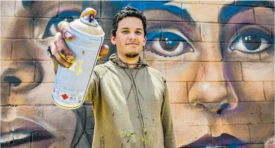  ?? HANSEL VÁSQUEZ ?? Jean Betancourt, conocido como Mr. Garek, muestra una lata de pintura frente a su mural, ubicado en la Vía 40 con calle 78.
