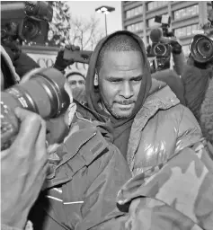  ?? —AFP photo ?? R. Kelly fights his way through photograph­ers outside of the Cook County jail after posting bond on Monday.