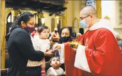  ?? Jessie Wardarski / Associated Press ?? Parishione­rs receive the sacrament from the Rev. Luis Gabriel Medina during Communion at Saint Bartholome­w Roman Catholic Church in the Queens borough of New York on Monday. This was the first in-person Mass at the church in almost four months.