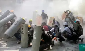  ?? Photograph: ?? Protesters take cover as they clash with riot police in Yangon on Sunday.