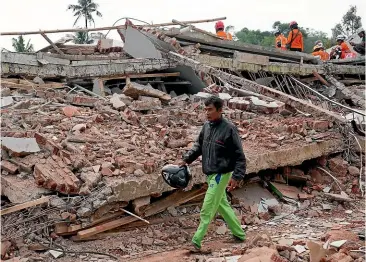 ?? AP ?? Enjot, 45, who lost 11 family members and his house, walks past the rubble of a building collapsed in Monday’s earthquake in Cianjur, West Java, Indonesia. More than 268 people were killed, with hundreds missing and injured, almost all in and around Cianjur. The toll was expected to rise.