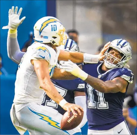  ?? Allen J. Schaben Los Angeles Times ?? JUSTIN HERBERT stiff-arms Micah Parsons before being tackled by the Cowboys linebacker in the fourth quarter at SoFi Stadium.