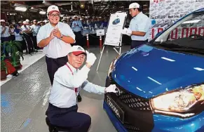  ??  ?? Perodua Auto Corporatio­n Sdn Bhd president Masanori Takahashi placing the Perodua logo on the one millionth Myvi while vice-president Datuk Zainal Abidin Ahmad and workers cheer him on.