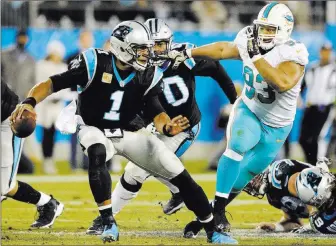  ?? Mike Mccarn ?? The Associated Press Panthers quarterbac­k Cam Newton scrambles under pressure from Miami Dolphins tackle Ndamukong Suh in the first half of Carolina’s 45-21 victory on Monday night in Charlotte, N.C.