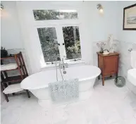  ??  ?? The master bath has tall windows made by Vintage Woodworks to match the home’s original ones. Marble tiles on the floor also flow up the walls. This ensuite is part of the newly expanded top floor that used to be an unused attic.
