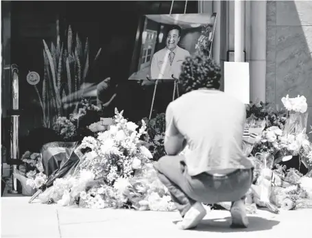  ?? AP PHOTO/ASHLEY LANDIS ?? Gabe Kipers, a neighbor of Dr. John Cheng, kneels at a memorial for him outside his office building on on Tuesday in Aliso Viejo, Calif. Cheng, 52, was killed in Sunday’s shooting at Geneva Presbyteri­an Church.