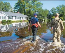  ?? Sean Rayford Getty Images ?? COAST GUARD OFFICER Lorenzo Ladaga, left, surveys a submerged street in Conway, S.C., on Friday. “The worst is still to come,” the governor warned.